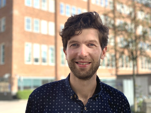 Daniel Nyqvist står framför en solbelyst tegelbyggnad.