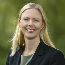 Anna Uvhagen, Norrenergis nya HR-chef. Leende blond kvinna med svart kavaj över grön blus med grön bakgrund.